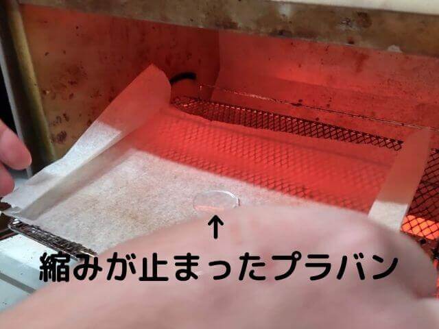トースターから縮みきったプラバンをクッキングシートごと取り出している写真
