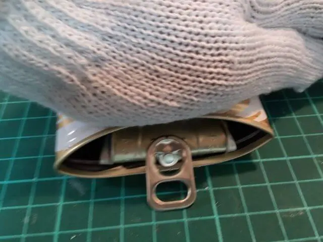 筒状になった呪術缶を切り取った呪術缶上部が入るくらいまで手で押して潰している写真