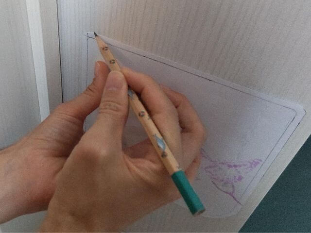 型紙にそって、キャットドア取り付け位置のドアにえんぴつで下書きをしているところの写真